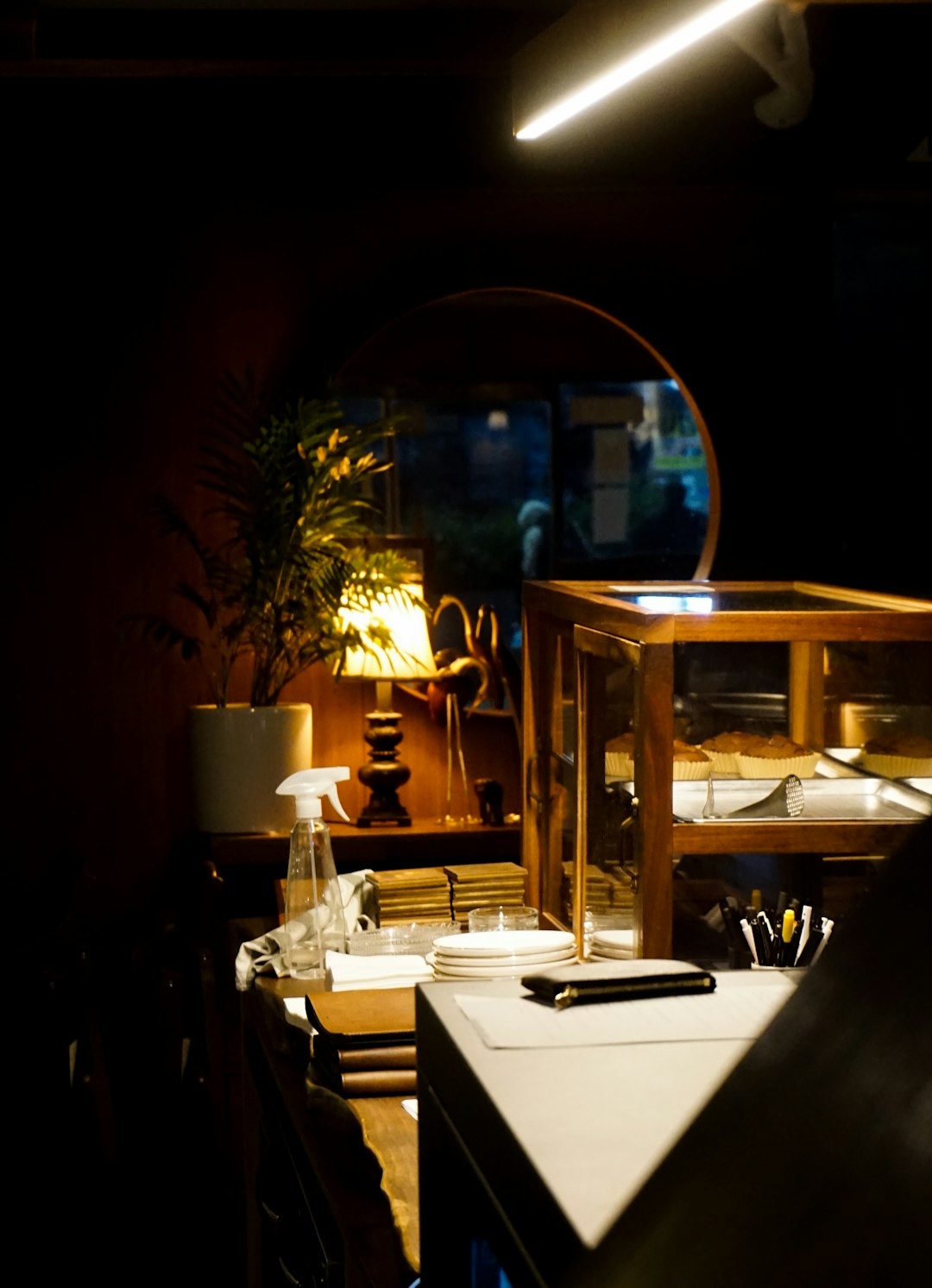 a-table-with-a-lamp-and-a-mirror-in-a-dark-room-aiend8ojuii